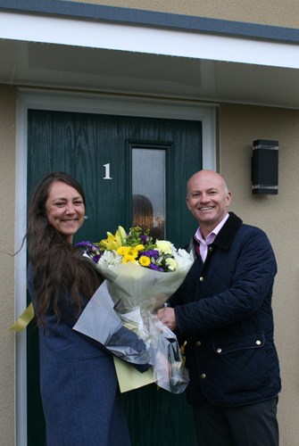Image of new tenant Miss Pavanello accepting a bouquet of flowers from Mid Devon District Council's Director of Operations, Andrew Pritchard