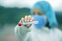 person wearing PPE and holding a test tube